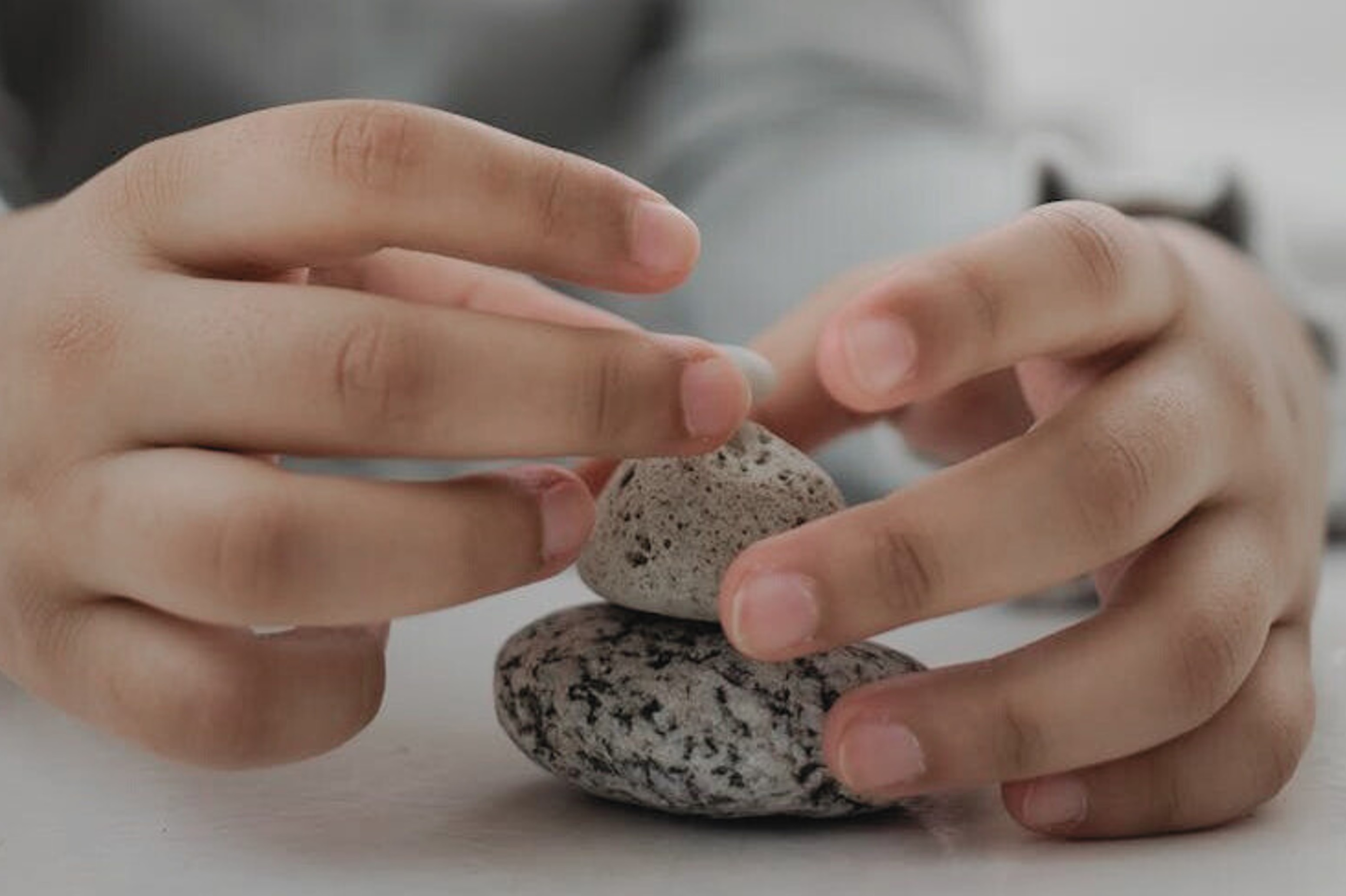 Un enfant empile des pierres sur une surface claire, illustrant la notion d'équilibre émotionnel