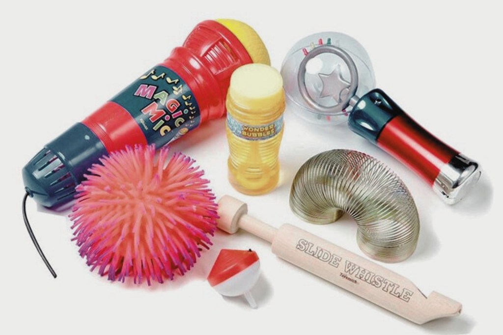 Une collection de renforçateurs, comprenant un microphone magique, une bouteille de bulles, une balle à picots, un sifflet à coulisse, un slinky et un tambourin.