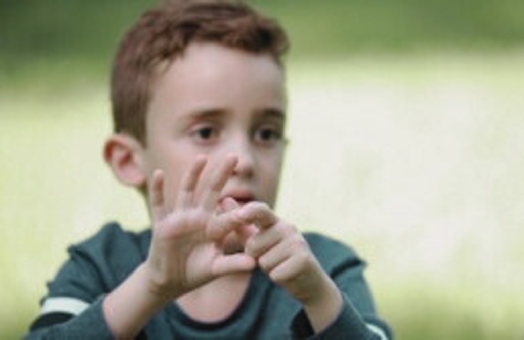 Un enfant montrant des gestes de communication avec ses mains, illustrant l'utilisation de la communication gestuelle.
