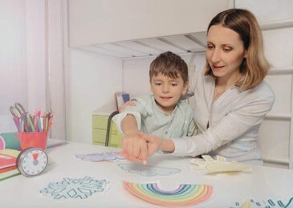 Une thérapeute enseigne le pointage à un enfant en le guidant main sur main. 