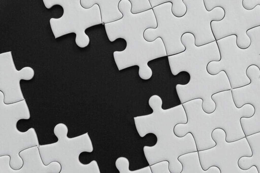 Un puzzle partiellement complété sur un fond noir, mettant en évidence les pièces manquantes.